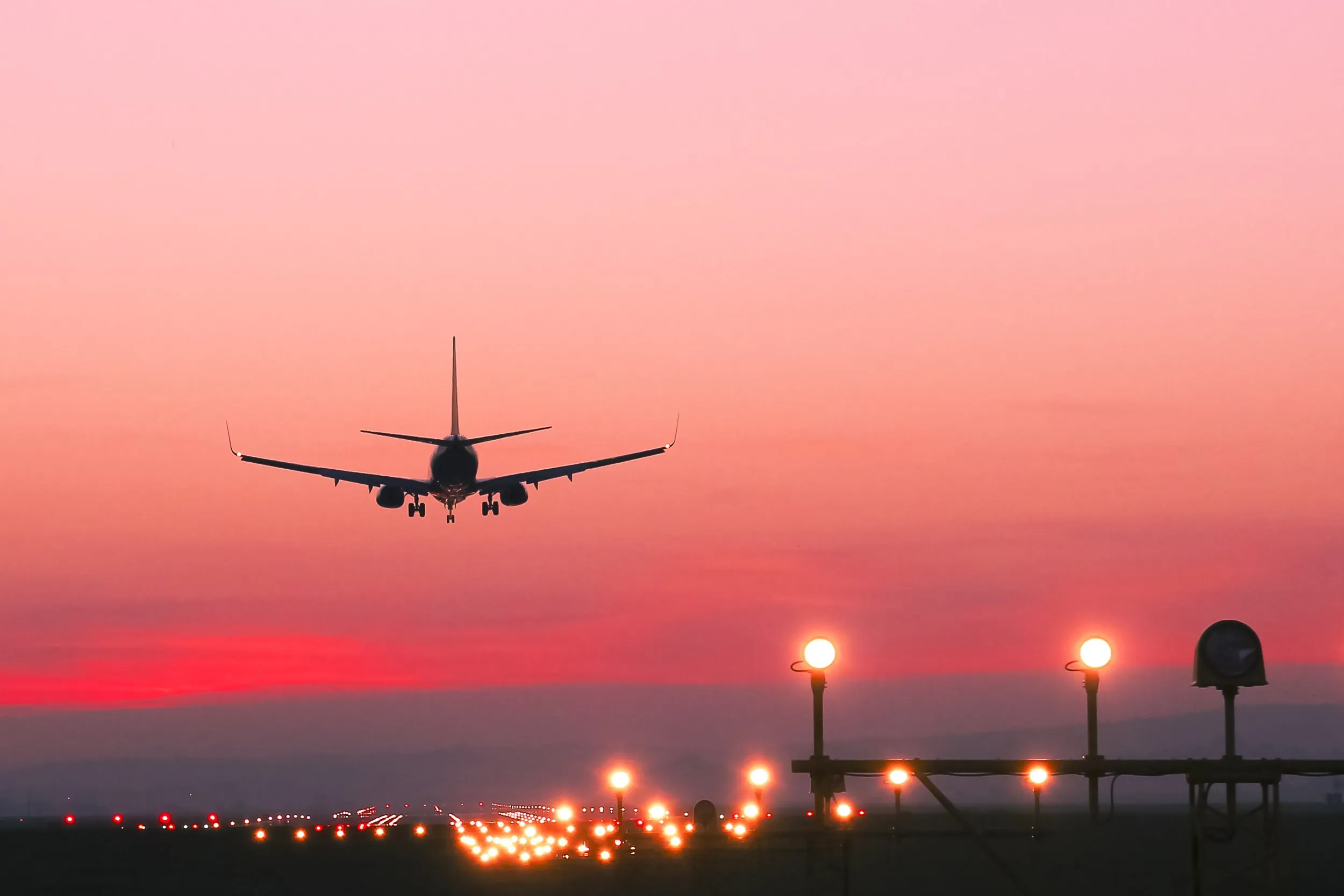 Aircraft on final approach at sunset over runway approach lighting