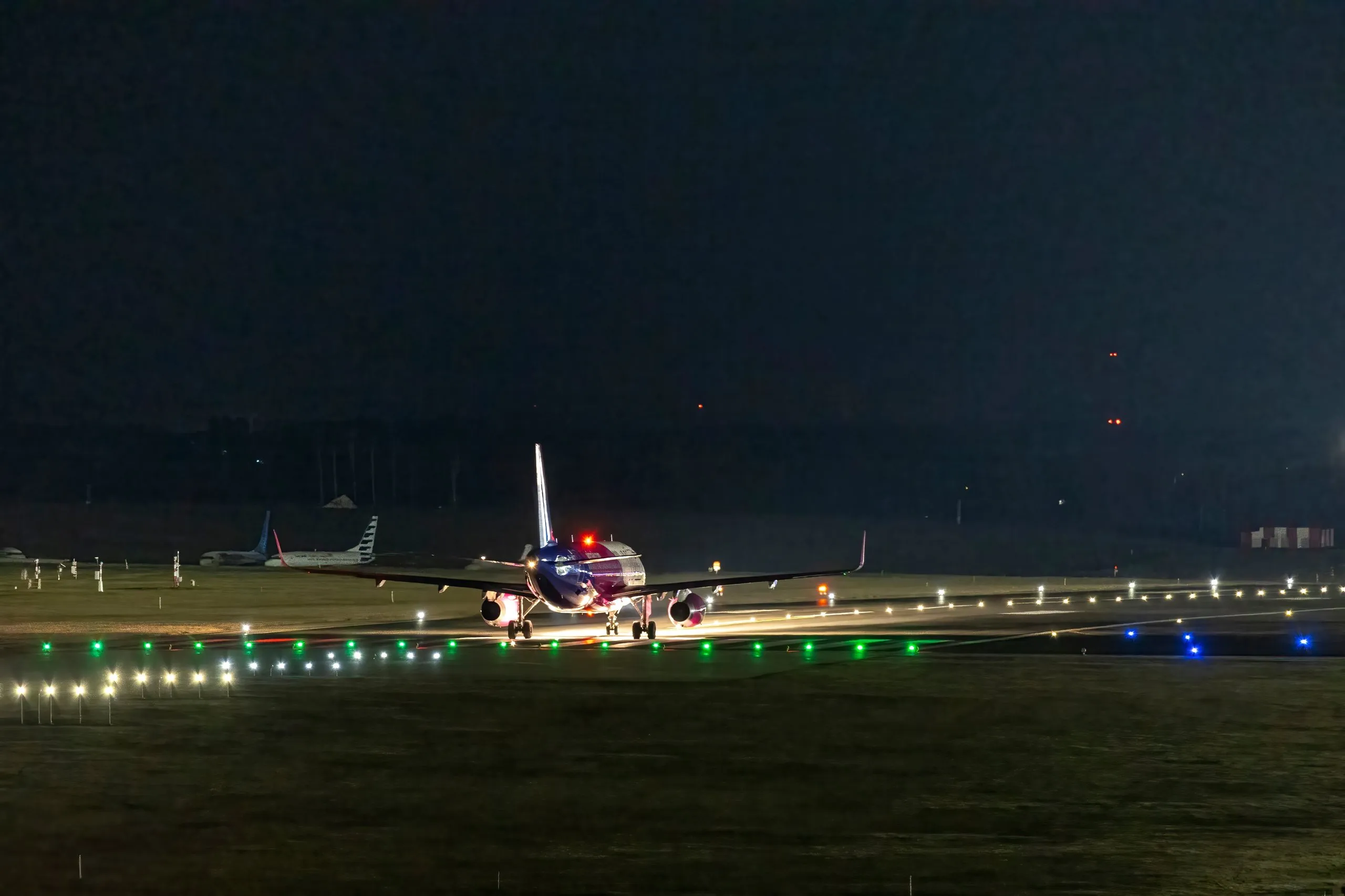 Aircraft lining up at night beside green taxiway centreline lights
